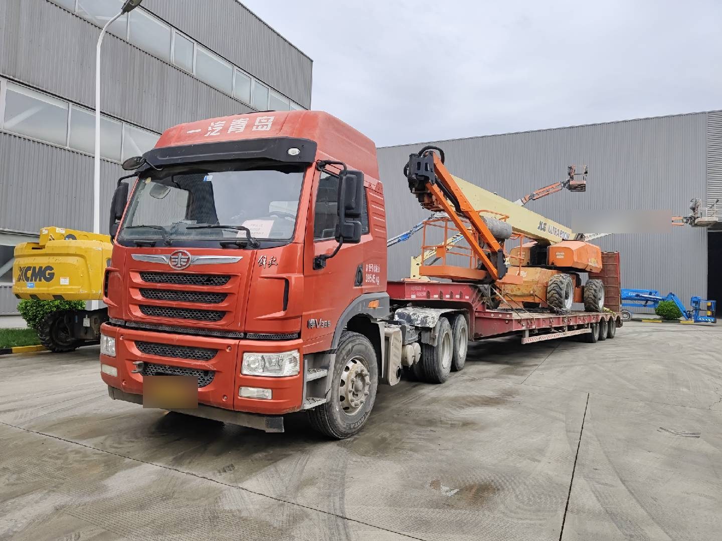 Flatbed truck delivering an aerial work platform to the yard